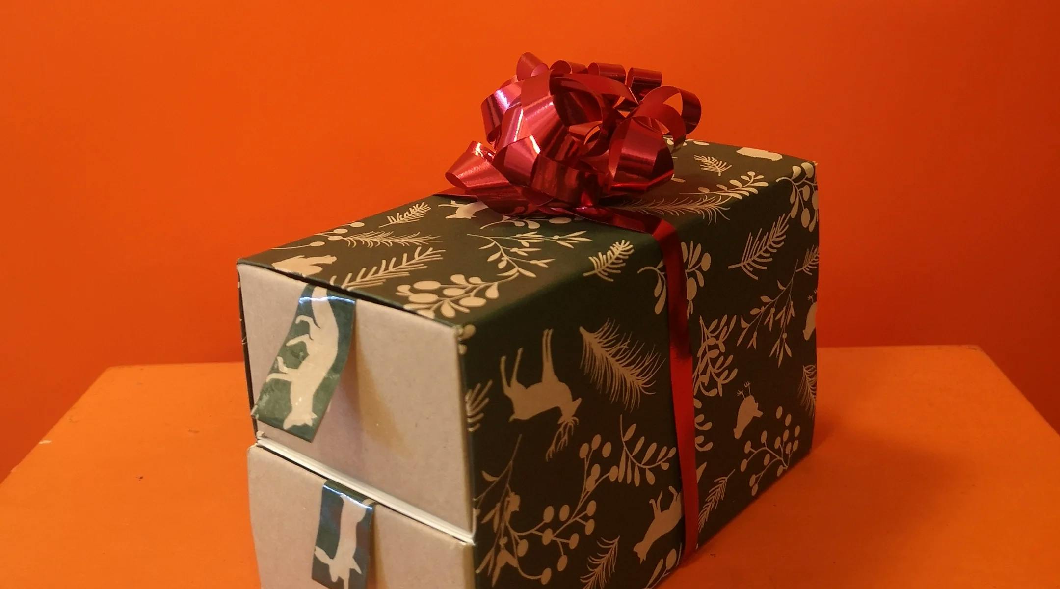 Adventskalender i form av en boks med to skuffer, pyntet med grønt julepapir og rød sløyfe på toppen.
