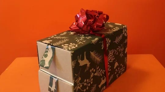 Adventskalender i form av en boks med to skuffer, pyntet med grønt julepapir og rød sløyfe på toppen.
